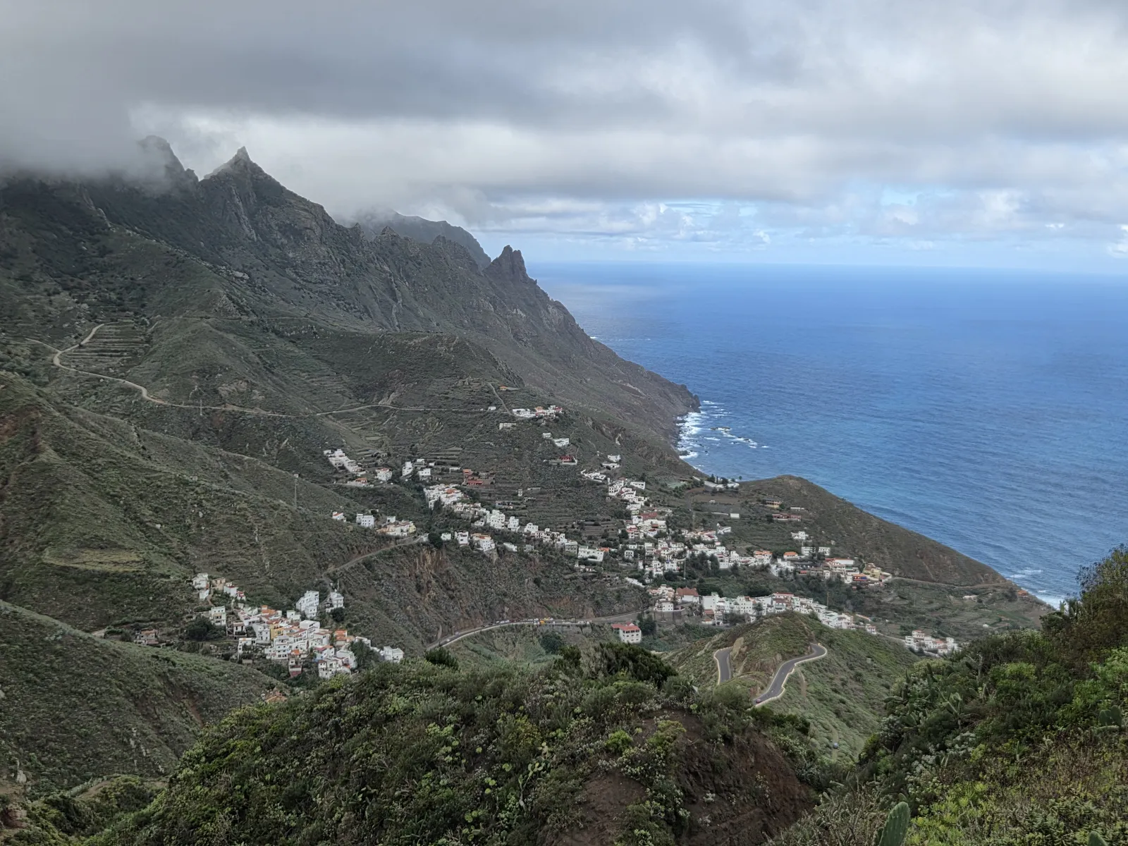 White houses and agricultural terraces in the Taganana valley beneath rugged mountains and low clouds