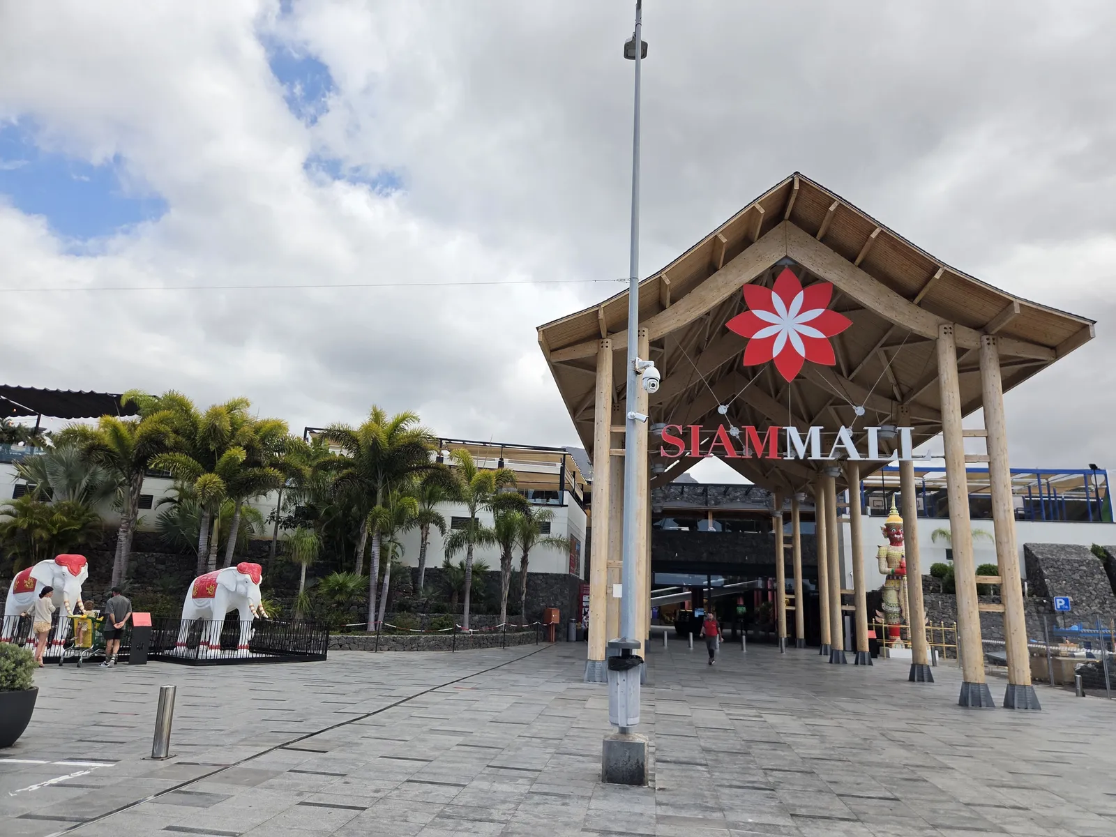 Timber-framed entrance and Siam Mall sign beside palm trees