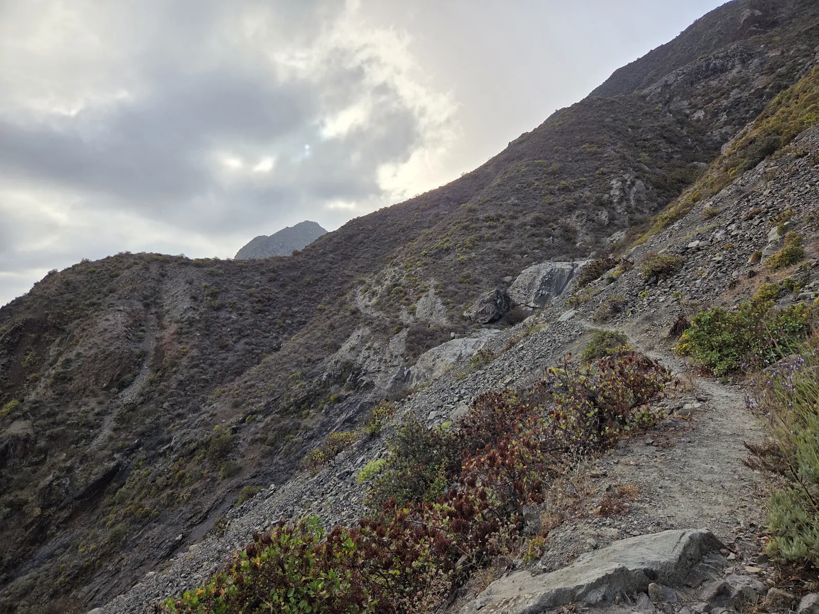 Narrow rocky footpath traversing a steep hillside near El Draguillo