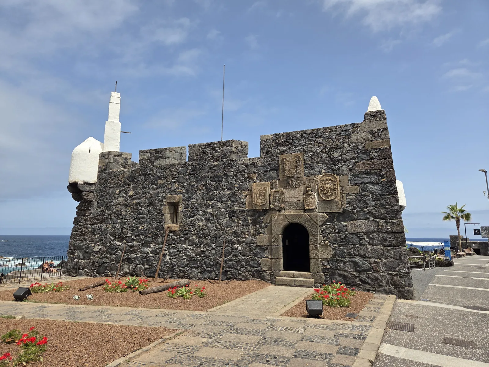 Dark stone walls and entrance of San Miguel Castle beneath white corner turrets
