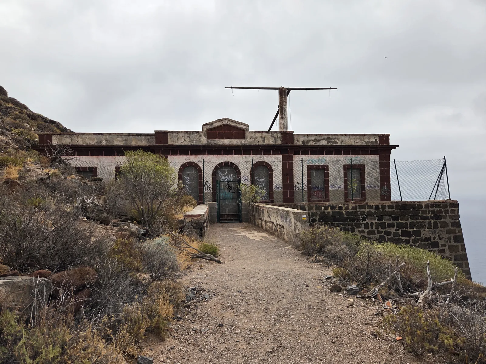 Weathered façade of El Semáforo with arched openings and an old signal mast above the entrance